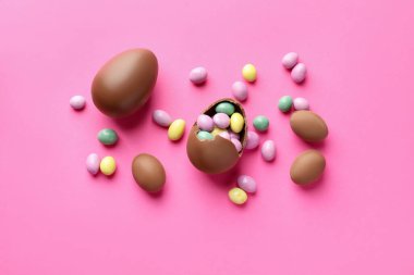 Çikolatalı Paskalya yumurtaları pembe arka planda şekerli, düz yatıyordu.