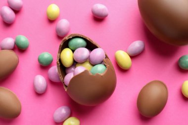 Çikolatalı Paskalya yumurtaları pembe arka planda şekerli, düz yatıyordu.