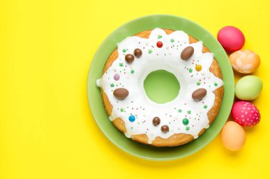 Lezzetli Paskalya pastası ve sarı arka planda boyanmış yumurtalar. Metin için boşluk