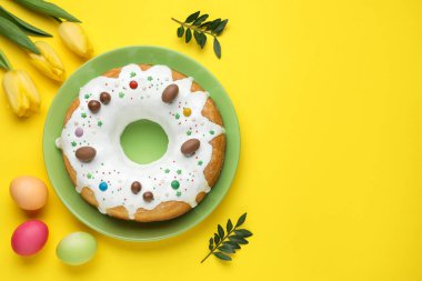 Lezzetli Paskalya pastası, boyanmış yumurtalar, güzel laleler ve sarı arka planda yeşil yapraklar. Metin için boşluk