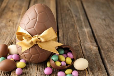 Mutlu Paskalyalar. Ahşap masada renkli şekerlemeli lezzetli çikolata yumurtaları, yakın plan. Metin için boşluk