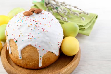 Lezzetli Paskalya pastası, boyanmış yumurtalar ve söğüt dalları beyaz ahşap masa üzerinde, yakın plan.