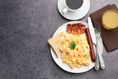 Lezzetli bir kahvaltı. Lezzetli çırpılmış yumurta, domuz pastırması, sosis ve ekmek gri desenli masada servis edilir. Metin için boşluk