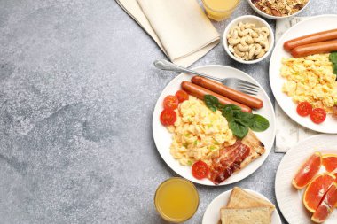 Lezzetli bir kahvaltı. Lezzetli çırpılmış yumurta, domuz pastırması, sosis ve domatesler gri desenli masa üzerinde servis ediliyor, düz yatak. Metin için boşluk