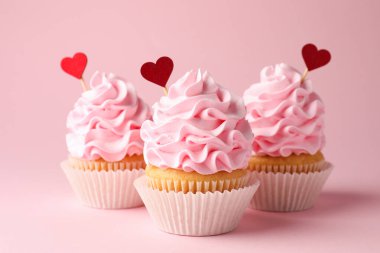 Sevgililer Günün kutlu olsun. Pembe arka planda kırmızı kalp kaplamalı lezzetli kekler, yakın plan.