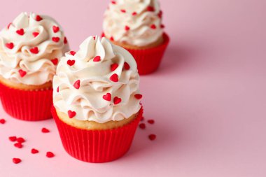 Sevgililer Günün kutlu olsun. Pembe arka planda kırmızı kalpleri olan lezzetli kekler, yakın plan. Metin için boşluk