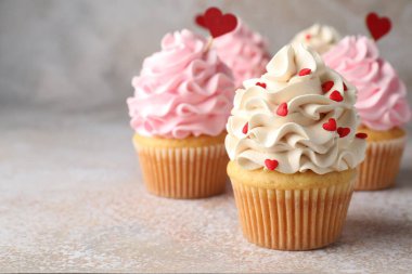 Sevgililer Günün kutlu olsun. Gri masada kırmızı kalpleri olan lezzetli kekler, yakın plan. Metin için boşluk