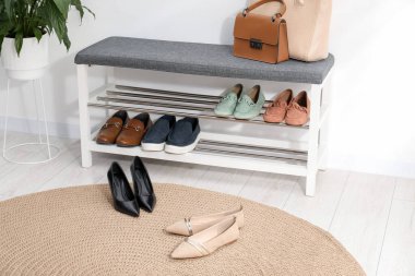 Farklı ayakkabılar, aksesuarlar ve beyaz duvarın yanındaki ev bitkilerinden oluşan ayakkabı deposu.