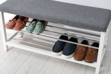 Beyaz duvarın yanında farklı ayakkabıları olan ayakkabı deposu tezgahı, yakın plan.