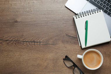 Ofis işyeri. Laptop, kahve ve kırtasiye malzemesi ahşap masada, düz yerde. Metin için boşluk