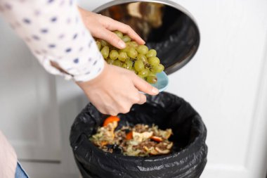 Mutfaktaki çöp tenekesine üzüm atan kadın, yakın plan.