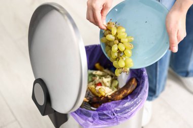 Mutfaktaki çöp tenekesine üzüm atan kadın, yakın plan.