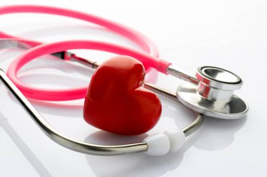 Beyaz arkaplanda steteskop ve kırmızı kalp, yakın plan.