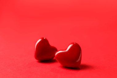 Sevgi. Kırmızı arka planda iki dekoratif kalp, yakın plan. Metin için boşluk