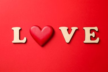 Aşk kelimesi ahşap harflerden ve kırmızı arka planda dekoratif kalpten yapılmıştır.