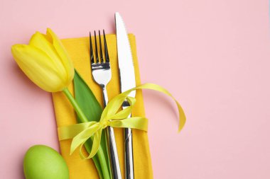 Paskalya kutlaması. Çiçekli masa dekoru ve pembe arka planda boyanmış yumurta, düz yatak. Metin için boşluk