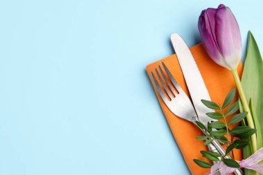 Paskalya kutlaması. Açık mavi arka planda çiçek dekoru olan şenlik masası, üst manzara. Metin için boşluk