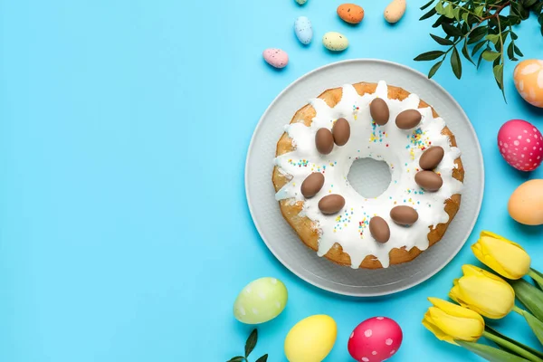 Lezzetli Paskalya pastası, boyanmış yumurtalar, güzel laleler ve açık mavi arka planda yeşil yapraklar. Metin için boşluk