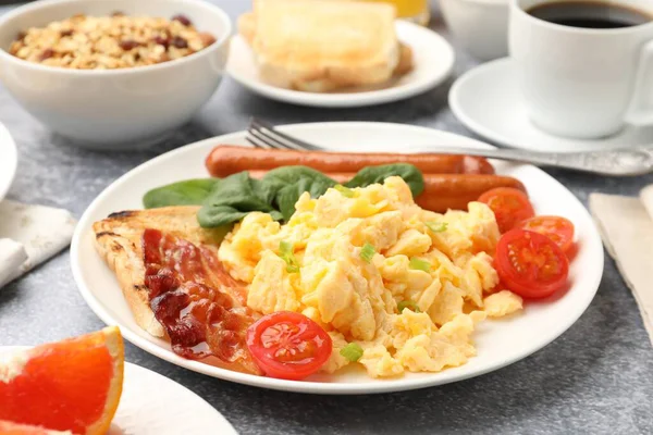 Lezzetli bir kahvaltı. Lezzetli omlet, pastırma, sosis ve domates. Gri desenli masada servis ediliyor. Yakın plan.