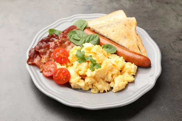 Lezzetli bir kahvaltı. Pastırmalı, sosisli ve domatesli leziz omlet. Gri desenli masa, yakın plan.