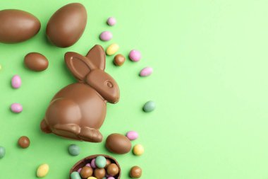 Çikolatalı Paskalya tavşanı ve açık yeşil arka planda yumurtalar. Metin için boşluk