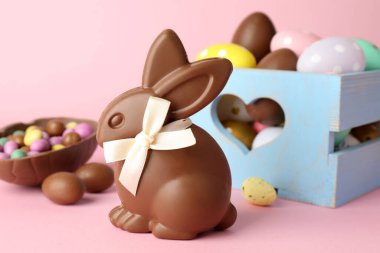 Çikolatalı Paskalya tavşanı ve pembe arka planda yumurtalar, yakın plan.