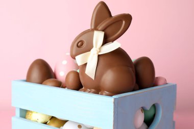 Çikolatalı Paskalya tavşanı ve pembe arka planda yumurtalar, yakın plan.
