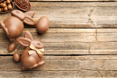 Çikolatalı Paskalya tavşanları ve yumurtalar ahşap masada, düz yerde. Metin için boşluk