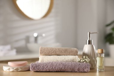 Temiz havlu yığını, çingene çiçekleri ve kozmetik ürünleri kapalı masa, yakın plan.