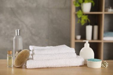 Temiz havlu yığını, çingene çiçekleri ve kozmetik ürünleri kapalı masa, yakın plan.