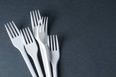 Plastik ambalaj. Gri arkaplan üzerinde tek kullanımlık çatallar, metin için boşluk ile düz uzanma