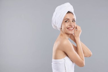 Saçları gri arka planda havluya sarılı güzel bir kadın, mesaj için yer var.