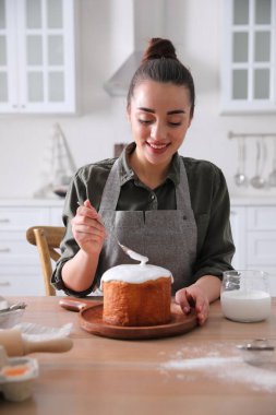 Genç bir kadın geleneksel paskalya pastasını mutfakta jöleli dekore ediyor.