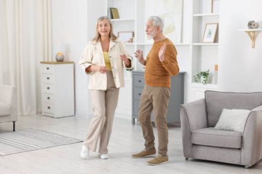 Mutlu yaşlı çift evde dans ediyor.