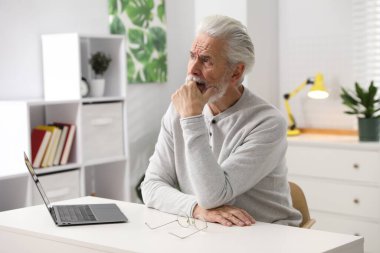 Hafıza kaybı. Bilgisayarlı son sınıf öğrencisi beyaz masada bir şeyler hatırlamaya çalışıyor.