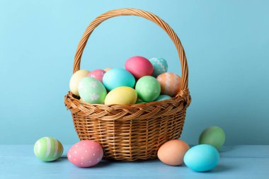 Masadaki sepetteki güzel Paskalya yumurtaları açık mavi arka planda