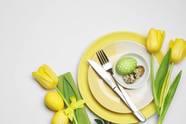 Paskalya kutlaması. Lale çiçekli şenlik masası, beyaz arka planda boyanmış bıldırcın yumurtaları, düz yatış. Metin için boşluk