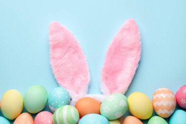 Mutlu Paskalyalar. Şirin tavşan kulakları ve açık mavi arka planda boyanmış yumurtalar.