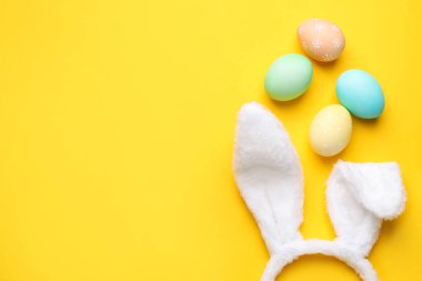 Mutlu Paskalyalar. Tatlı tavşan kulakları ve sarı arka planda boyanmış yumurtalar. Metin için boşluk