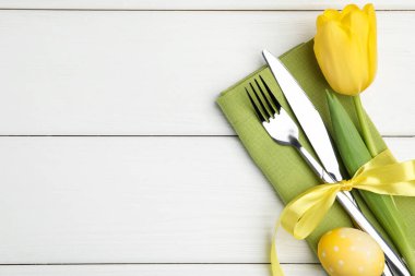 Paskalya sofrası. Lale ve beyaz ahşap arka planda boyalı yumurta ile güzel gümüş takımlar, üst manzara. Metin için boşluk