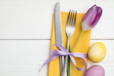 Paskalya sofrası. Lale ve beyaz ahşap arka planda boyanmış yumurtaları olan güzel gümüş takımlar, üst manzara. Metin için boşluk