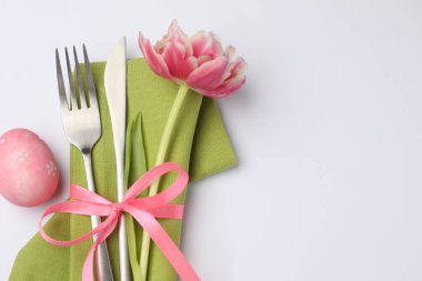 Paskalya sofrası. Beyaz arka planda lale ve boyalı yumurta ile güzel gümüş takımlar, üst manzara. Metin için boşluk