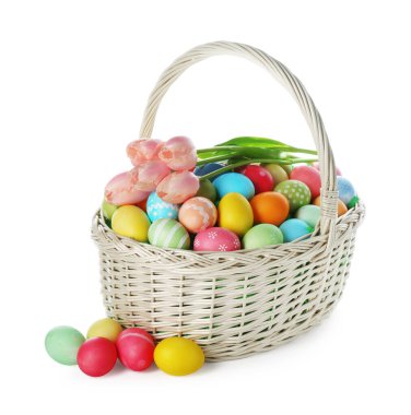 Boyanmış Paskalya yumurtaları ve hasır sepetin içindeki güzel laleler beyaza izole edilmiş.