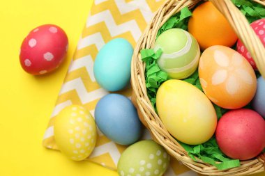 Sarı arka planda boyanmış yumurtaları olan Paskalya sepeti.