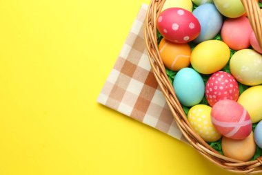 Sarı arka planda boyanmış yumurtaları olan Paskalya sepeti, üst manzara. Metin için boşluk