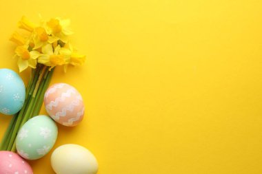Paskalya yumurtaları ve turuncu arka planda güzel nergisler. Metin için boşluk