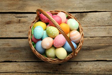 Tahta masanın üstünde boyanmış yumurtalar olan Paskalya sepeti, üst manzara.