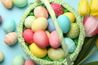 Açık mavi arka planda boyanmış yumurtaları olan Paskalya sepeti düz uzanıyordu.
