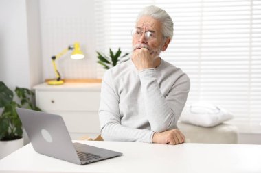Hafıza kaybı. Bilgisayarlı son sınıf öğrencisi beyaz masada bir şeyler hatırlamaya çalışıyor.