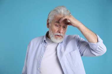 Hafıza kaybı. Kıdemli adam açık mavi arka planda bir şey hatırlamaya çalışıyor.
